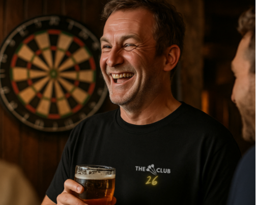 The 26 Club Black Tee being worn by man in pub playing darts